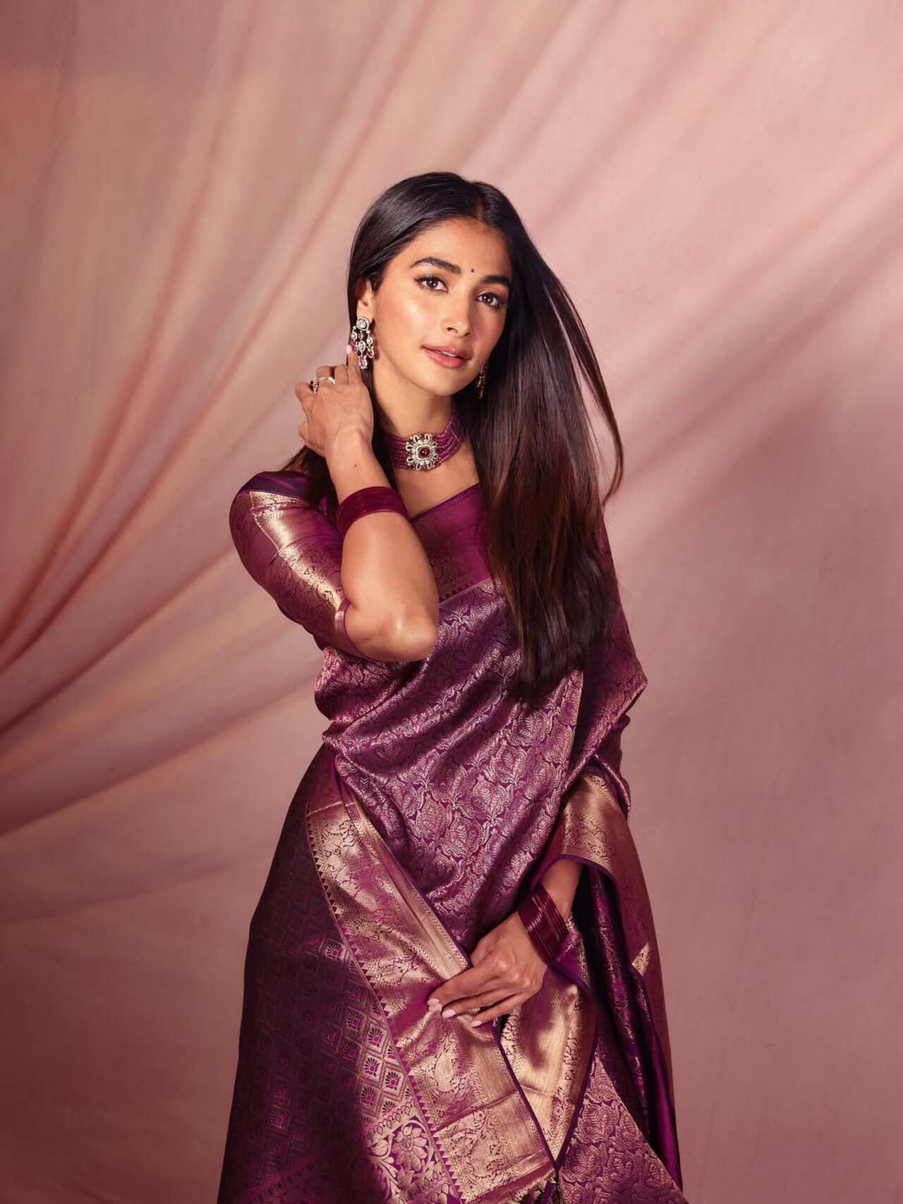 Pooja has always been a kanjeevaram girl, and she stunned in a jamun-purple kanjeevaram saree, with golden threadwork all across the drape. She paired the saree with a matching blouse, featuring a deep neck and a beaded knot. She even pulled off the accessory department by opting for a beaded choker and heavy earrings